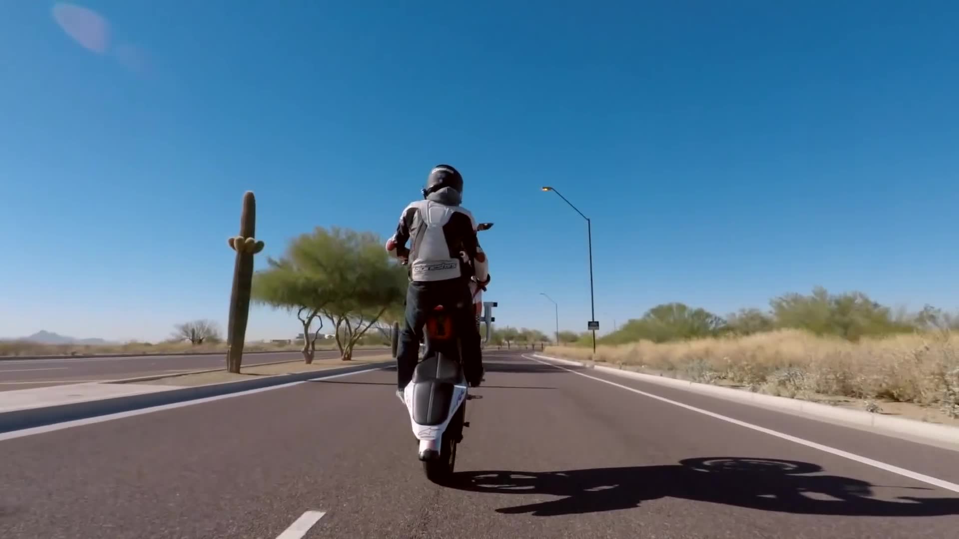 Motorcycle rider attempts tricks and stunts inside concrete skate park
