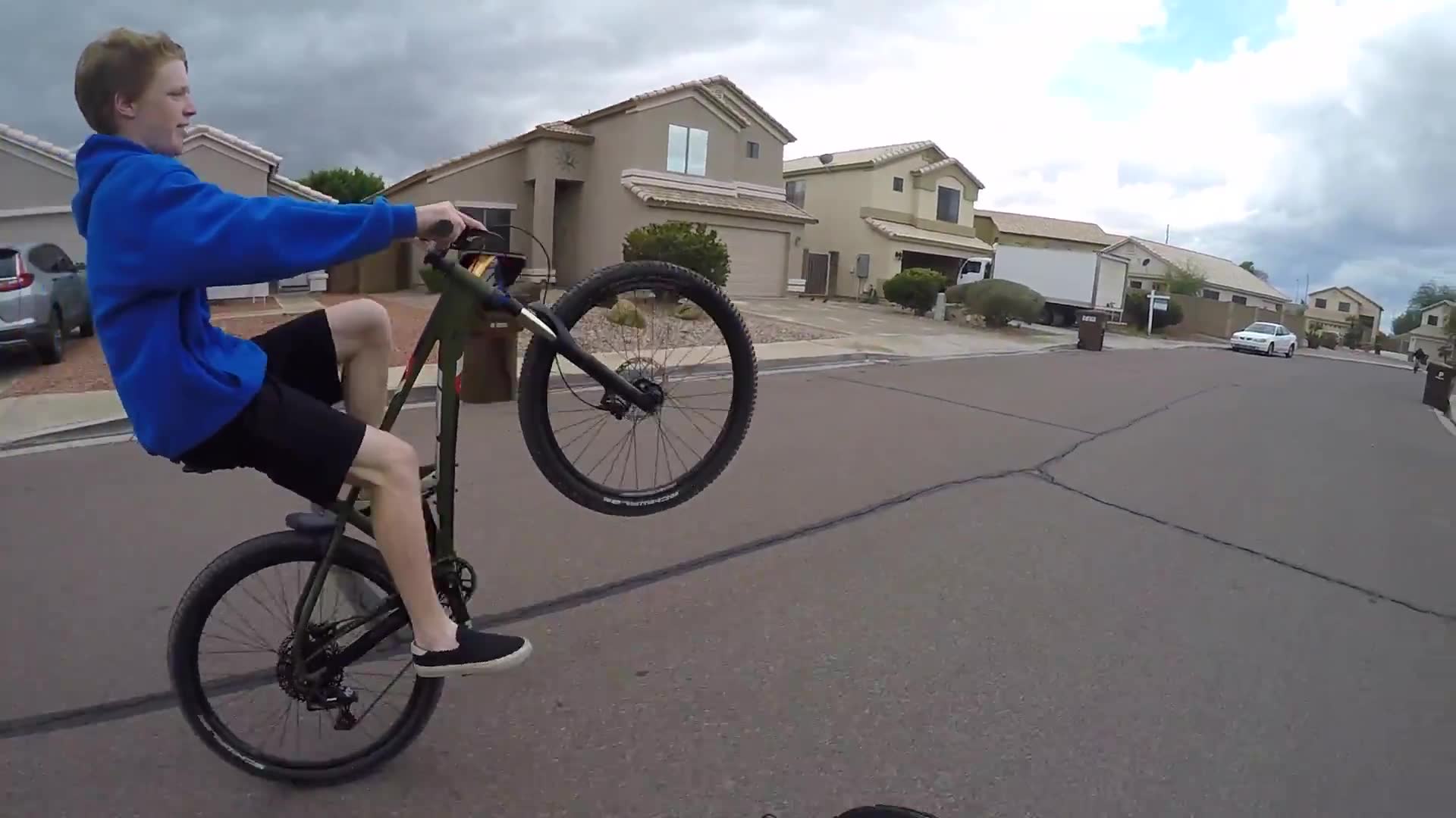 Children demonstrate impressive bicycle wheelie abilities to motorcyclists