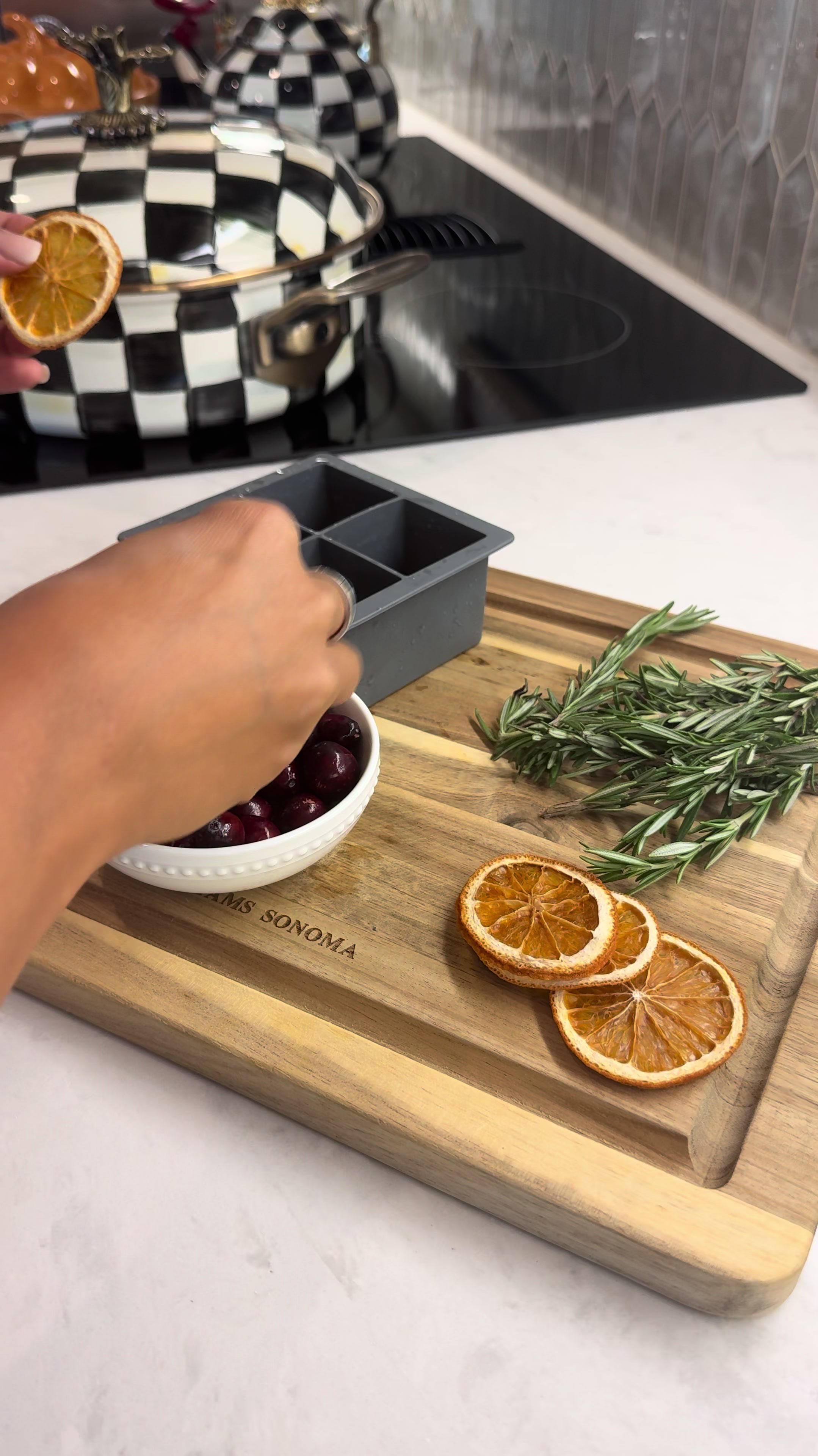 Making infused ice cubes for evening cocktails with dried orange rosemary dark cherries