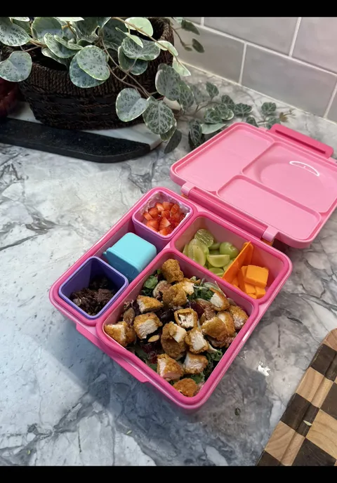 Nutritious lunchbox chicken pieces, dressed kale, and yogurt with mix-ins