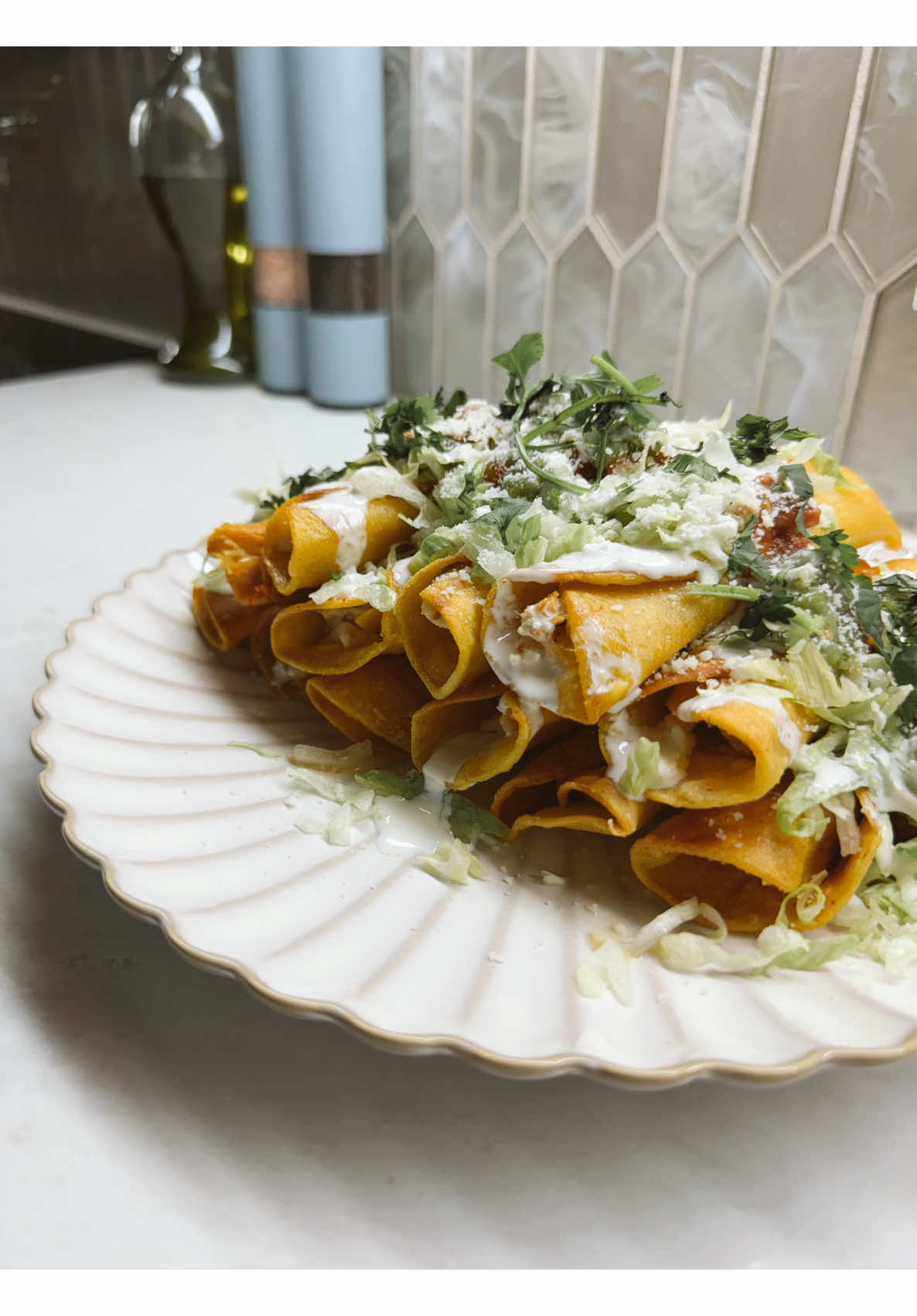 Homemade crispy golden taquitos flautas topped with crema shredded lettuce queso and cilantro