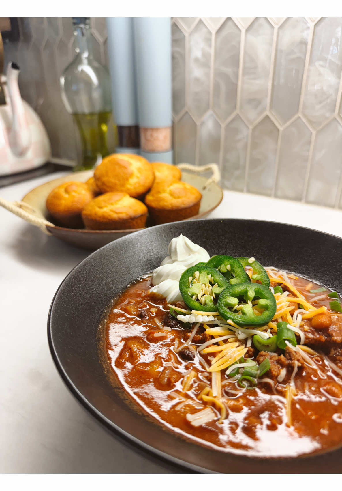 Hearty homemade chili with corn muffins sour cream shredded cheese jalapenos