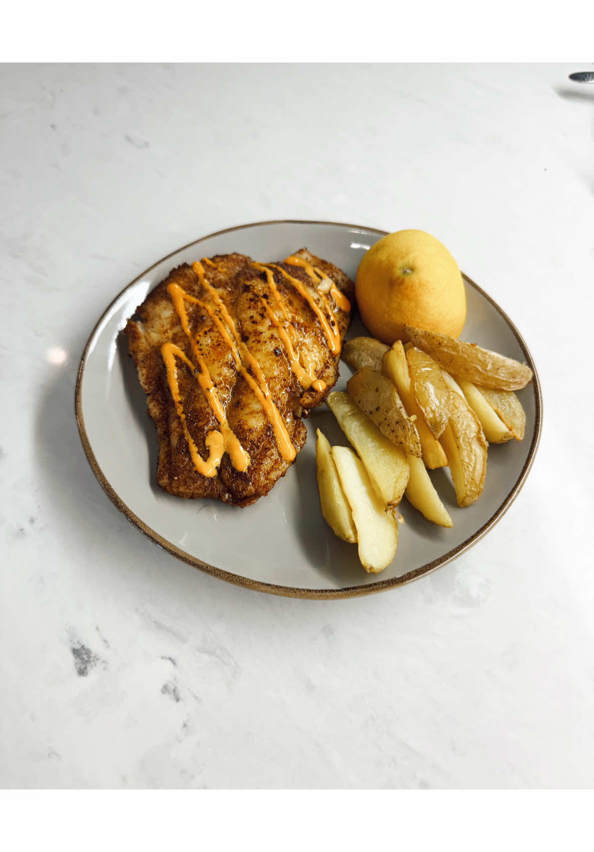 Pan fried fish or chicken drizzled with orange sauce potato wedges and lemon for sunday