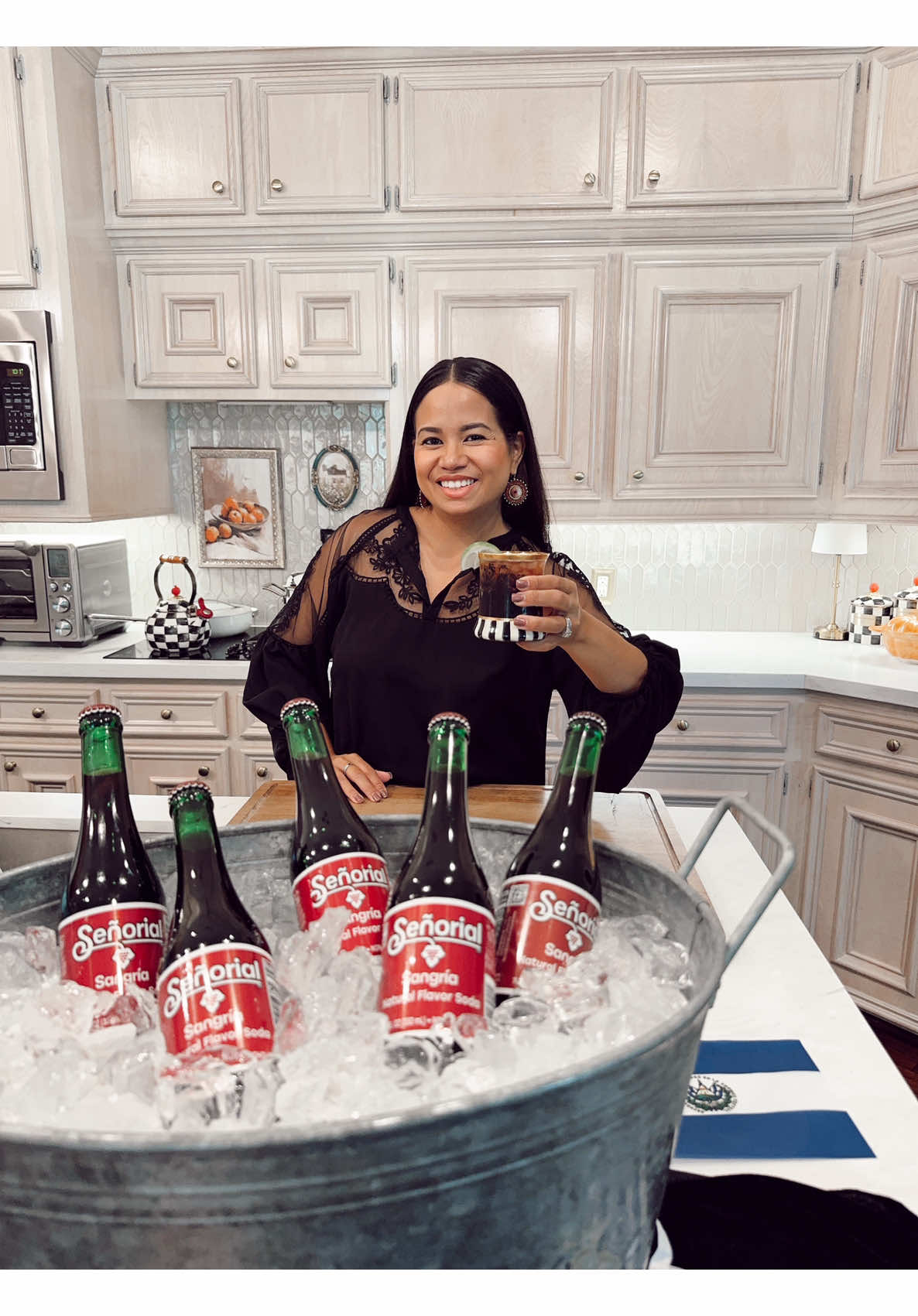 Happy woman shows senorial sangria soda display and mixed drink recipe in kitchen
