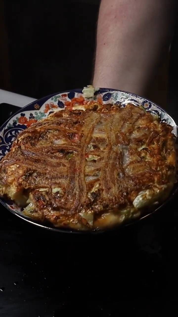 Japanese savory pancake layered with cabbage, pork, and okonomiyaki sauce